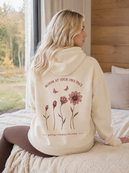 Šviesiai kreminis džemperis moterims su gobtuvu ir „Bloom At Your Own Pace“ gėlių spauda nugaroje