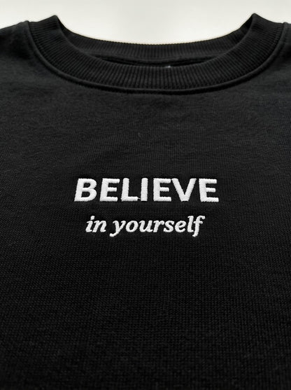 Juodas moteriškas džemperis su siuvinėtu užrašu „Believe in Yourself“