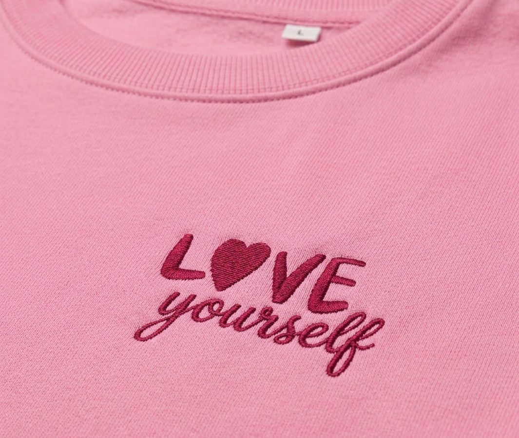 Siuvinėtas LOVE yourself užrašas ant rožinio džemperio