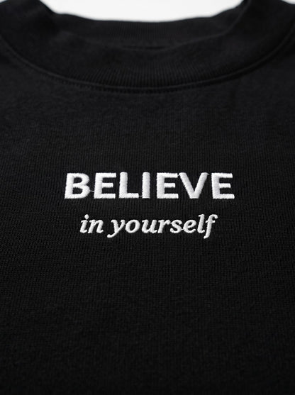Kokybiško balto siuvinėjimo „BELIEVE in yourself“ detalė ant juodų moteriškų marškinėlių.