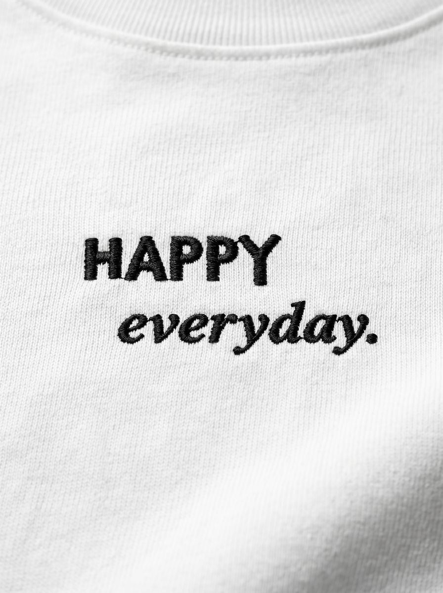 Kokybiško juodo siuvinėjimo „HAPPY everyday.“ detalė ant baltų moteriškų marškinėlių.