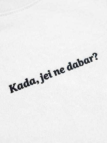 Kokybiško juodo siuvinėjimo „Kada, jei ne dabar?“ detalė ant baltų moteriškų marškinėlių audinio.