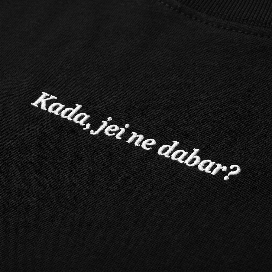 Kokybiško balto siuvinėjimo „Kada, jei ne dabar?“ detalė ant juodo moteriškų marškinėlių audinio.